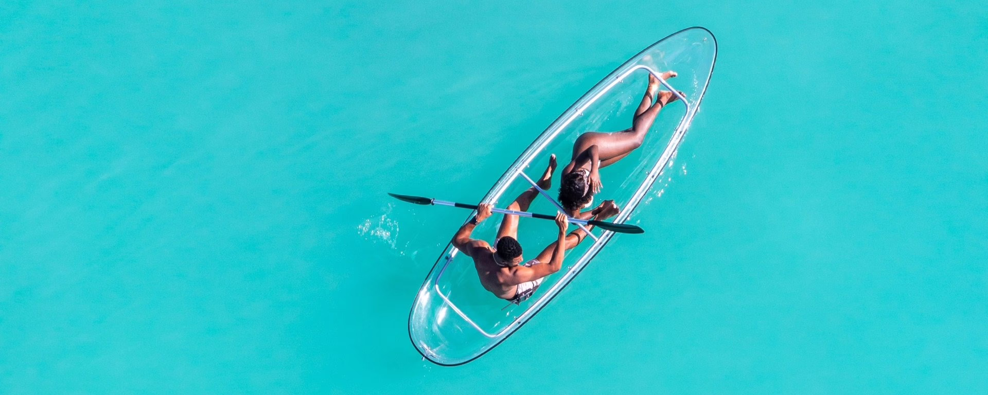 Aerial view of two people in a clear-bottom kayak on turquoise water, Grenada Concierge Inc.